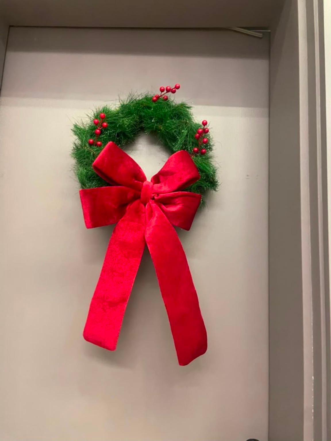 Green door wreath with a large red ribbon