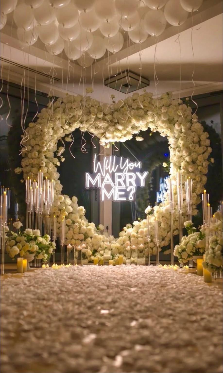 Gold-toned floral heart with a proposal sign in a covered setting